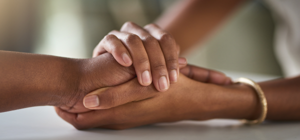 Closeup of two people holding hands. Comforting someone with problem gambling.