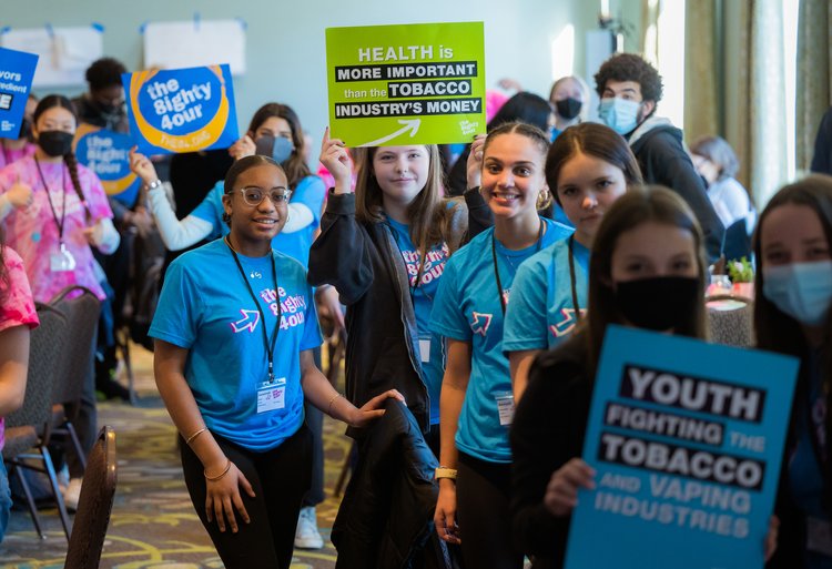 teenager in blue t-shirts holding signs in preparation for a rally