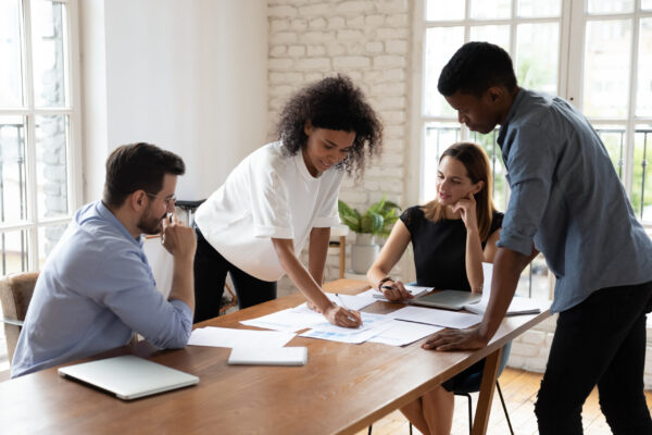 Motivated diverse colleagues analyzing paper report in office.